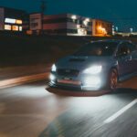 Tesla Model 3 з яскравими фарами під час нічної поїздки